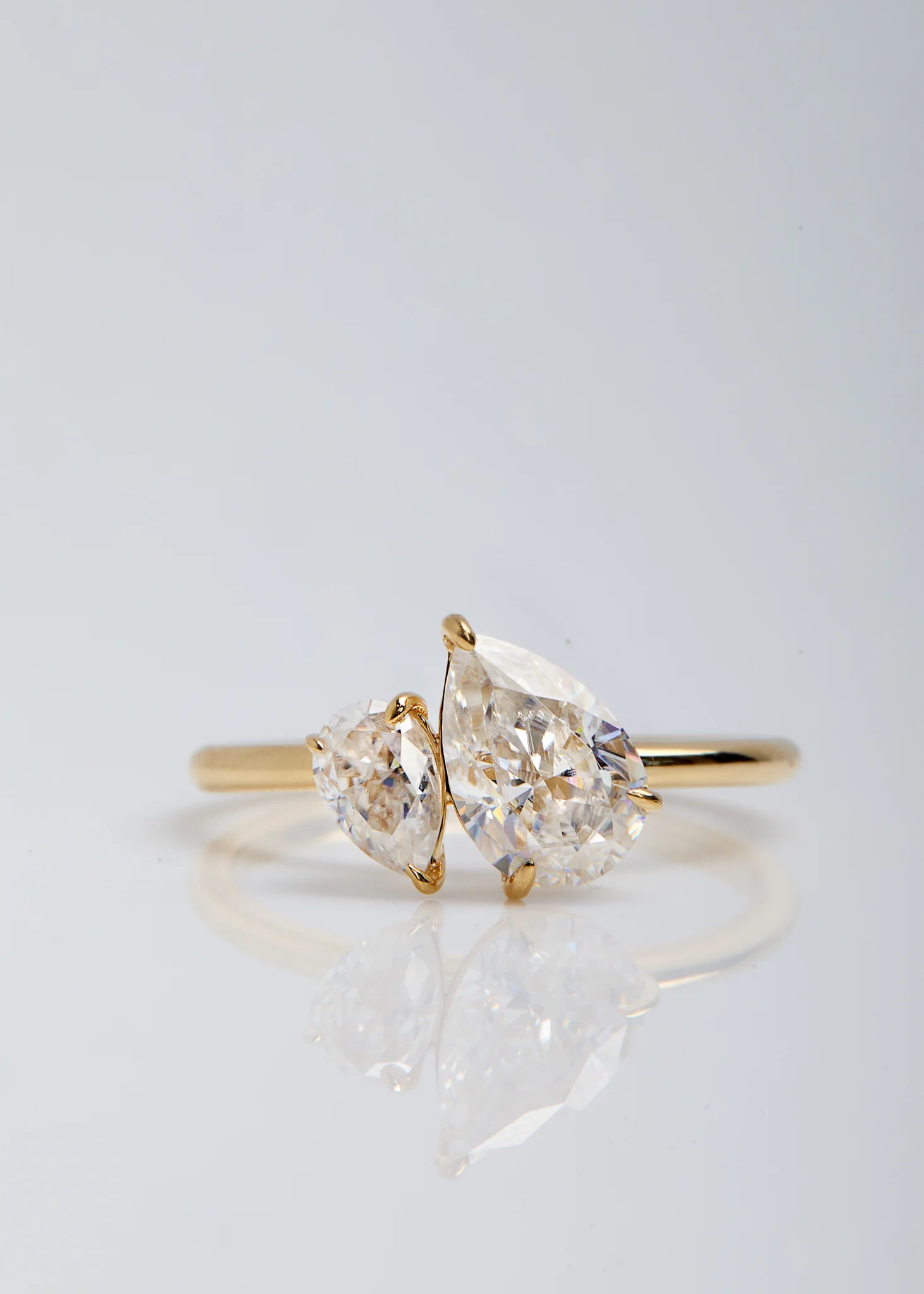 Gold ring with two pear-shaped moissanite on a light gray background