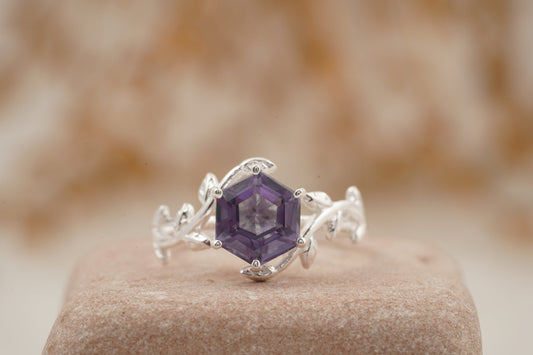 Silver ring with a purple gemstone on a stone surface